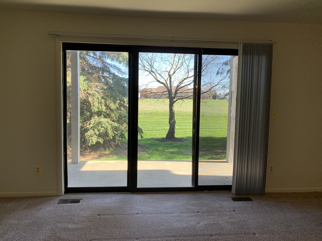 an empty living room with glass doors and a view of a field