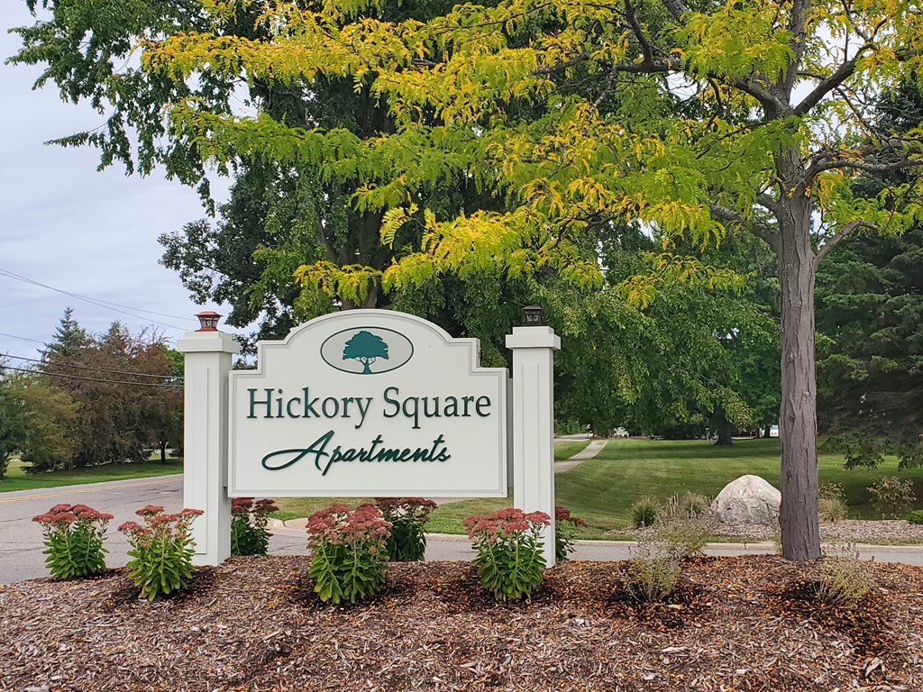 a sign for hickory square apartments in front of a tree