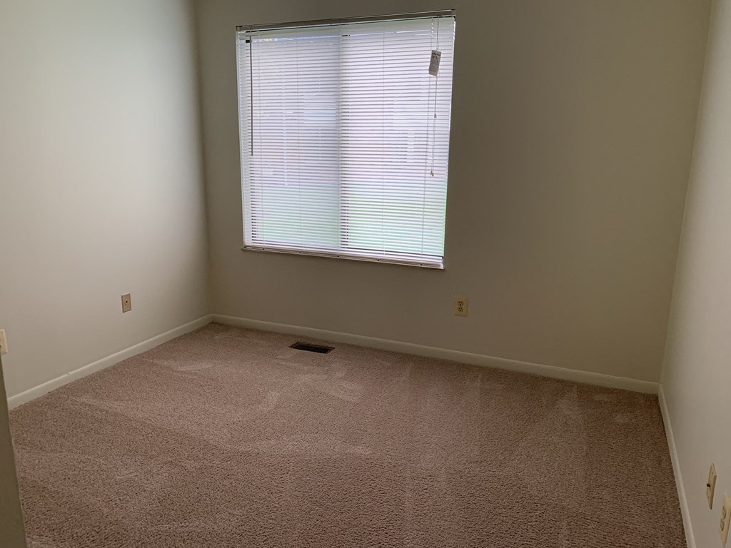 an empty room with a window and carpeting