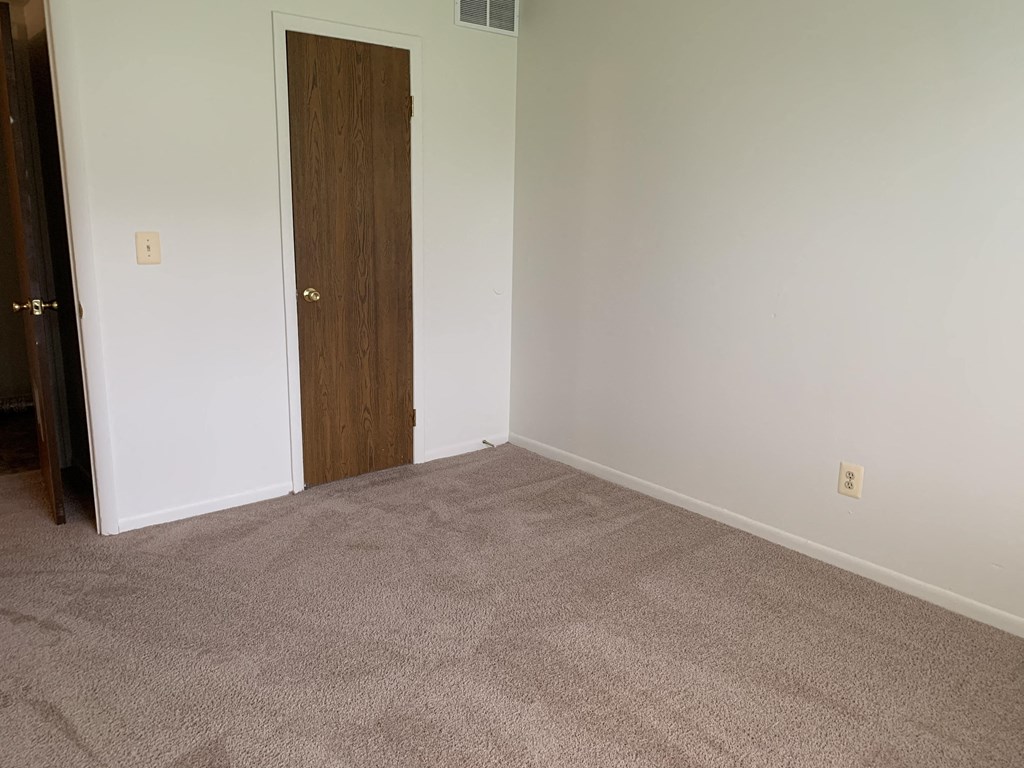 a room with a carpeted floor and a wooden door