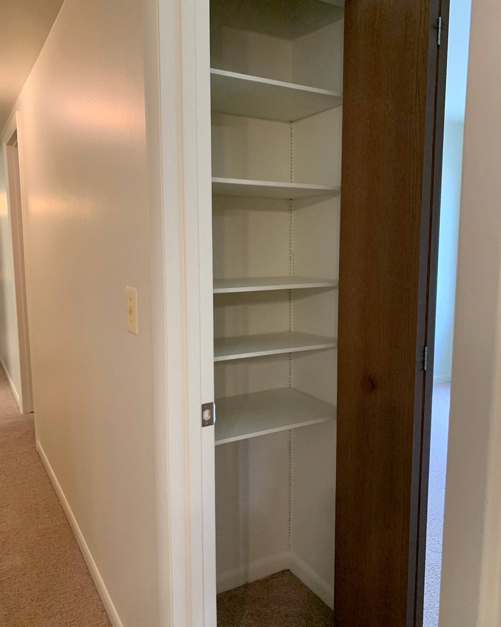 a closet with white shelves and a wooden door