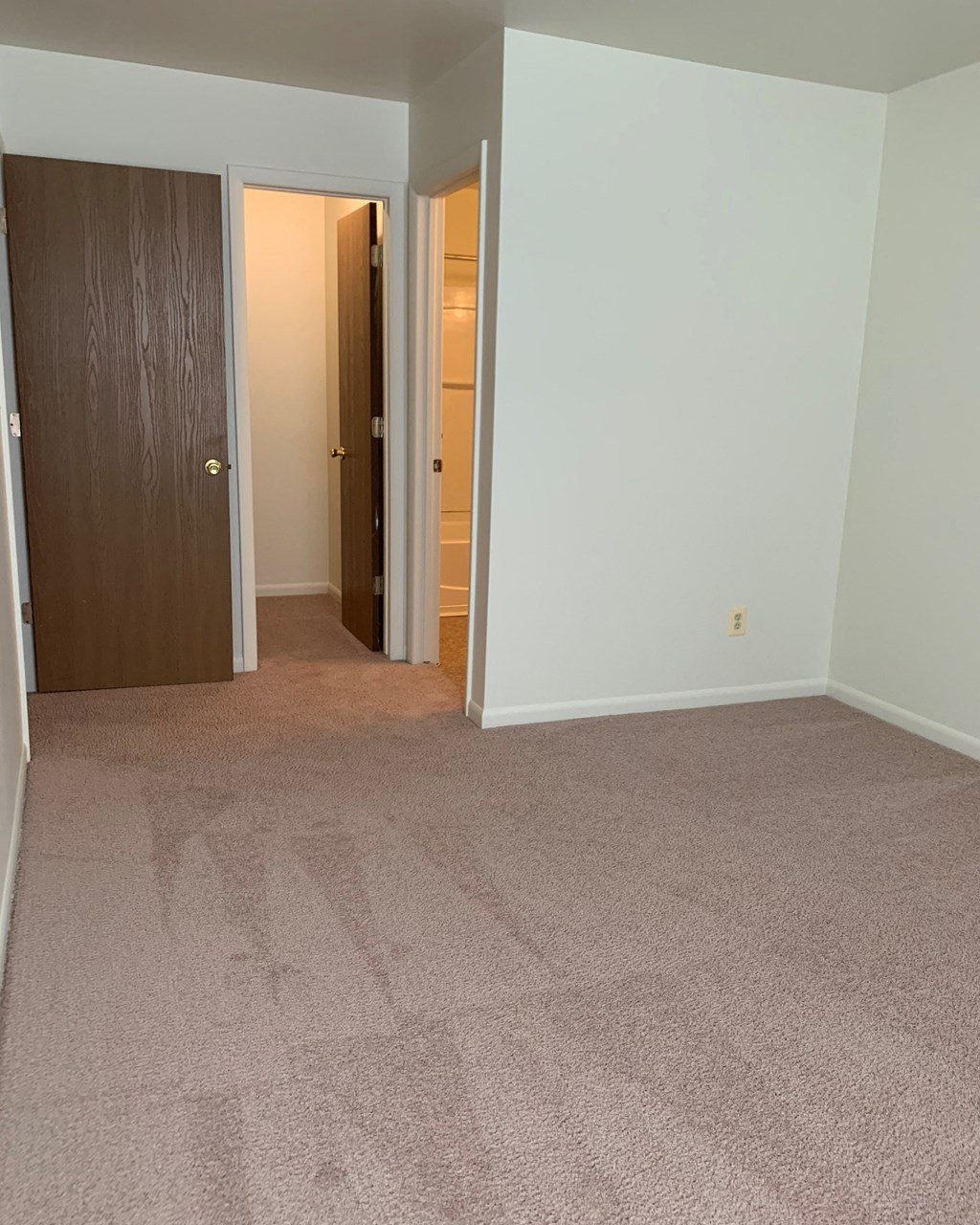 a bedroom with a carpeted floor and a door to a hallway