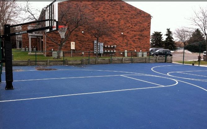a blue basketball court in front of a brick building