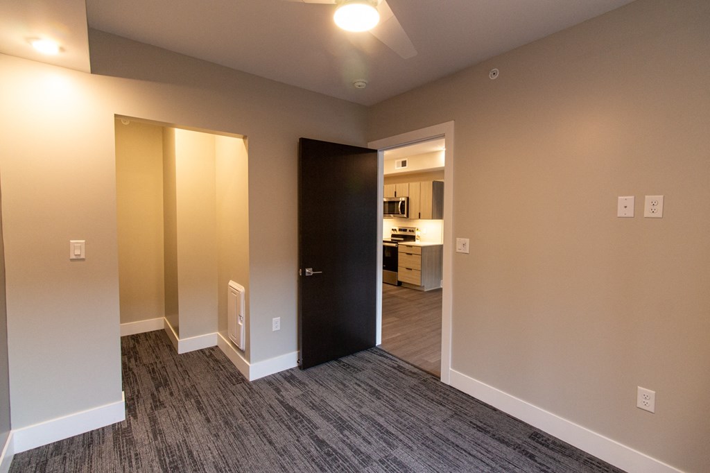 an empty living room and hallway with a door to a kitchen