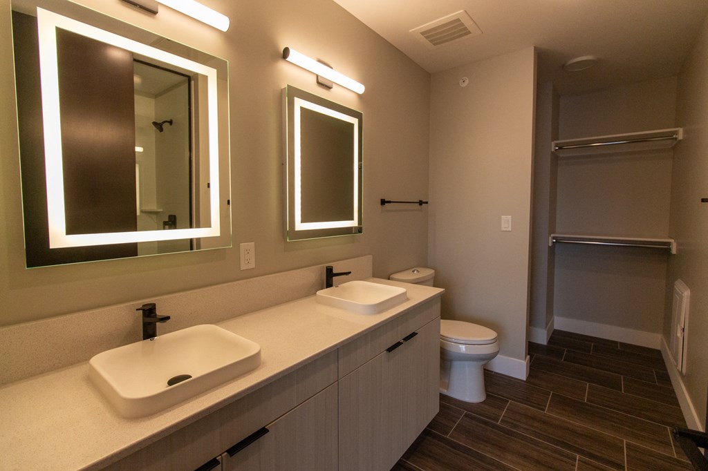a bathroom with two sinks and two mirrors and a toilet