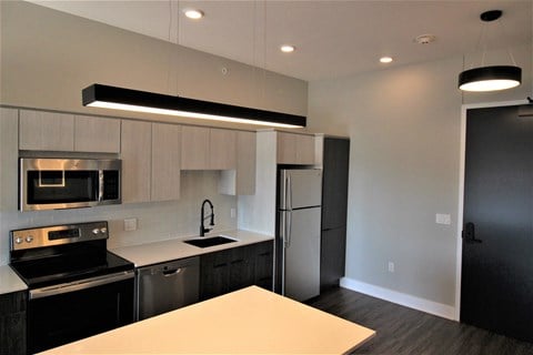 a kitchen with black and white cabinets and stainless steel appliances