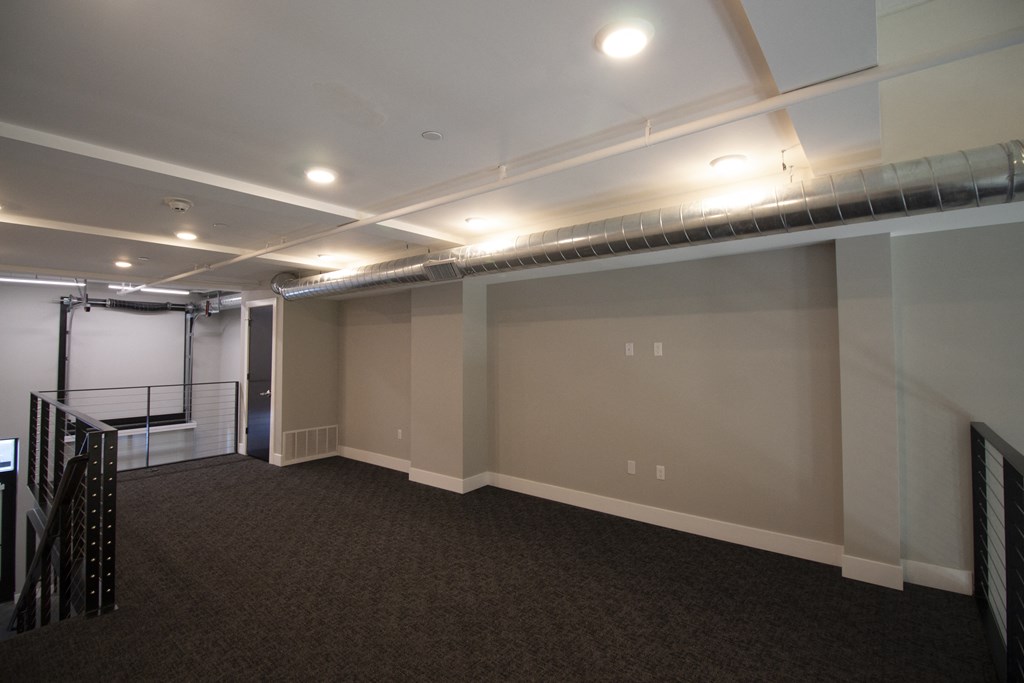 a room with a carpeted floor and a projector screen on the wall