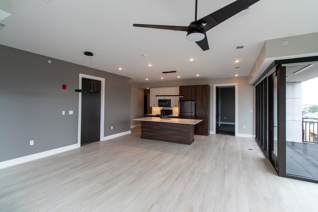 a renovated living room with a kitchen and a ceiling fan