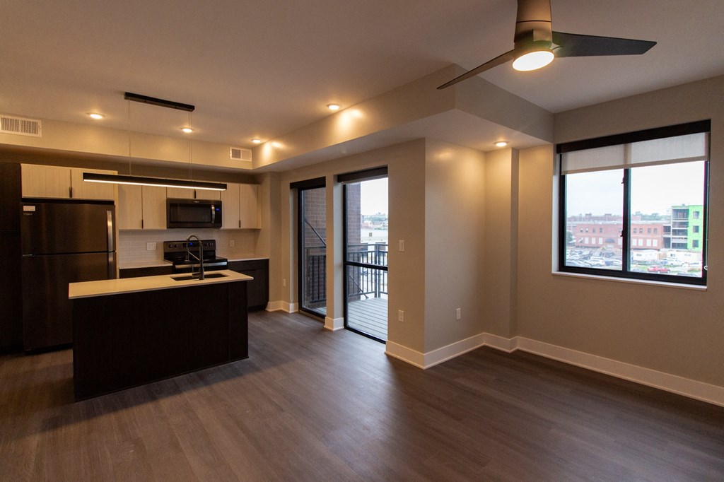 an empty living room with a kitchen and a balcony