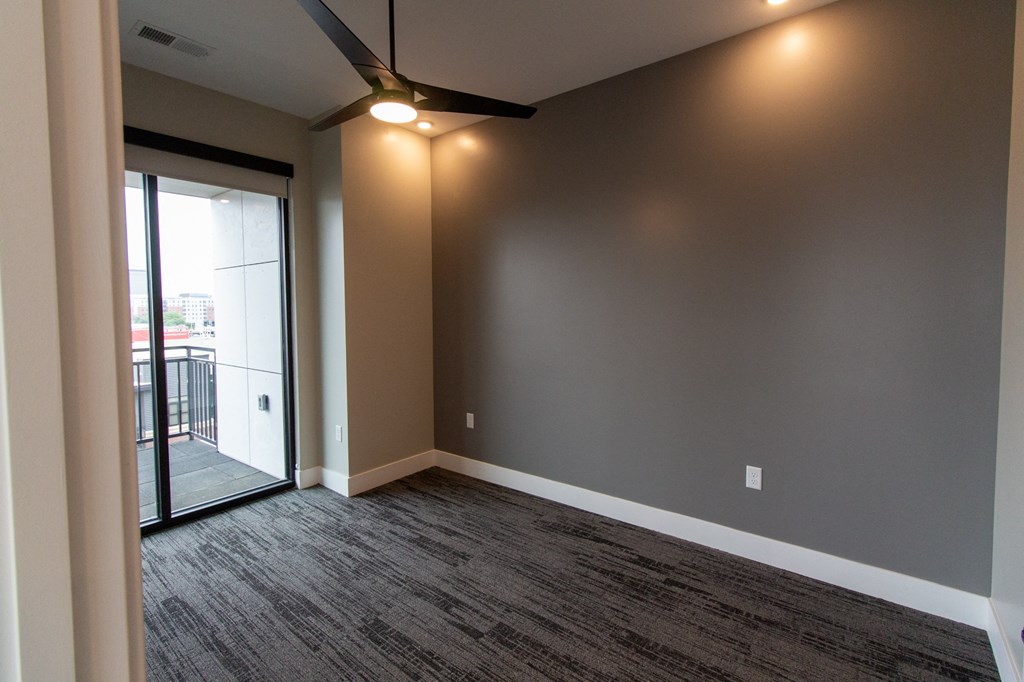 an empty living room with a sliding glass door to a balcony