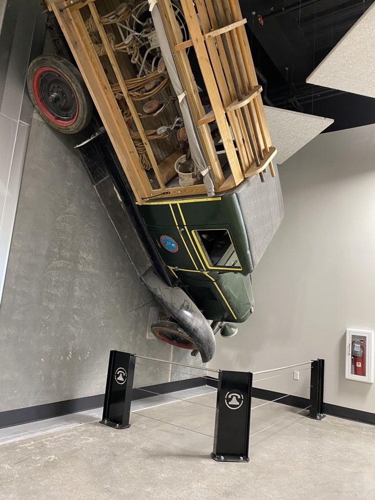 an old car hanging from the ceiling of a museum