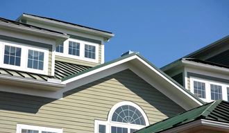 a green house with white windows and a blue sky