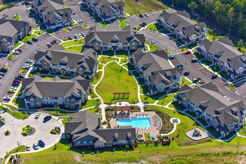 A bird's eye view of a Creekside at Providence with houses, cars, and a swimming pool.