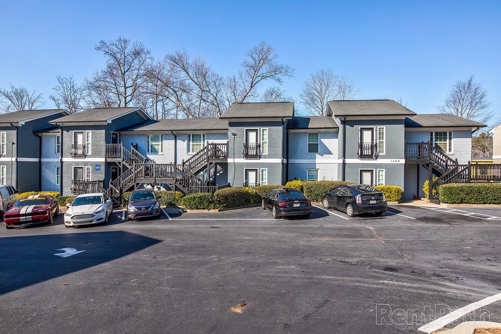 a row of apartments with cars parked in a parking lot
