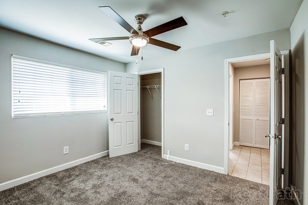 a bedroom with a ceiling fan and closet