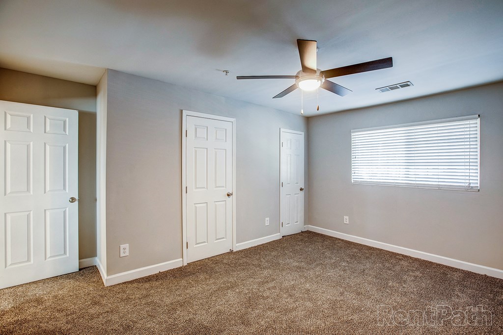 a bedroom with a ceiling fan and two doors