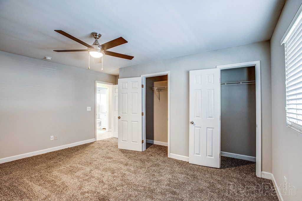 a bedroom with a ceiling fan and two closets