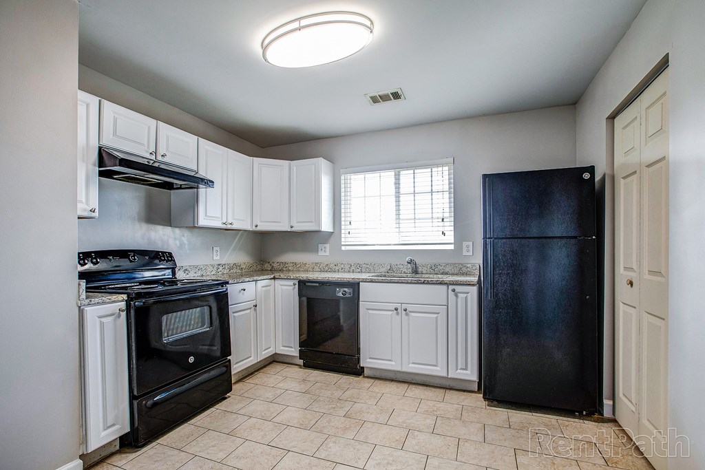 a kitchen with white cabinets and black appliances