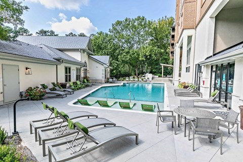 A pool surrounded by chairs and tables.