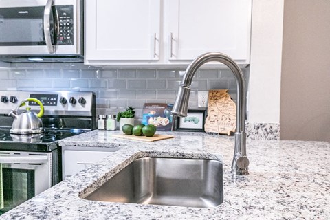 a kitchen with granite counter tops and a stainless steel sink