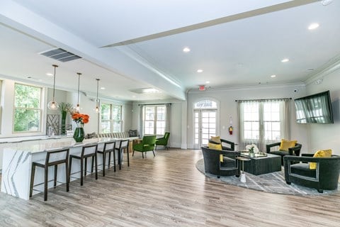 a living room with a bar and a dining room with chairs and a table