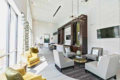 A modern clubroom with a yellow sofa and a glass chandelier.