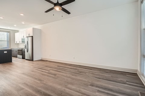 A room with a ceiling fan and a refrigerator.