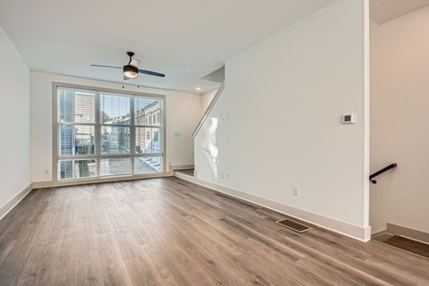 A room with a ceiling fan and a window with blinds.