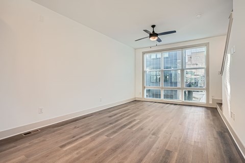 A room with a ceiling fan and wooden flooring.