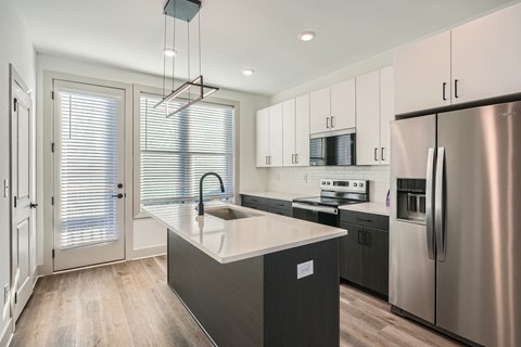 A modern kitchen with a stainless steel refrigerator and a center island.