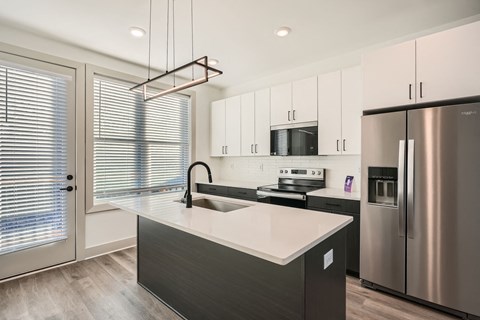 A modern kitchen with a stainless steel refrigerator and a sink with a black faucet.