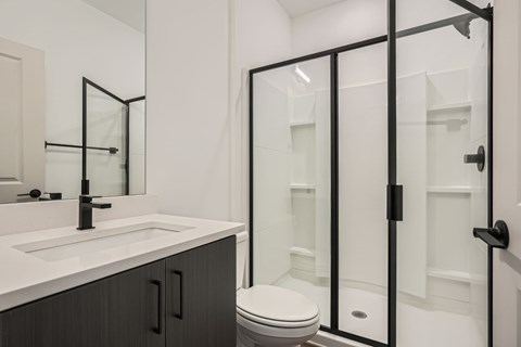 A white bathroom with a toilet, sink, and shower.