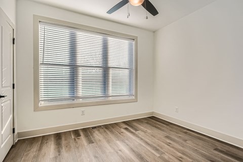 A room with a window covered by white blinds and a ceiling fan.