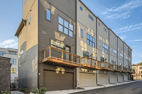 A modern building with a balcony and garage doors.