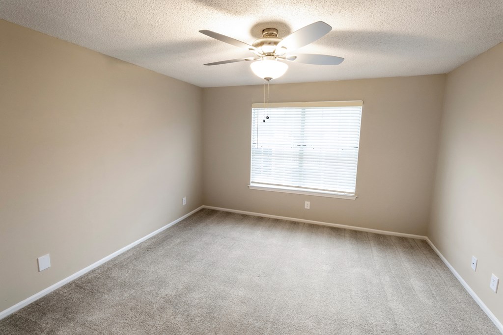 an empty room with a ceiling fan and a window
