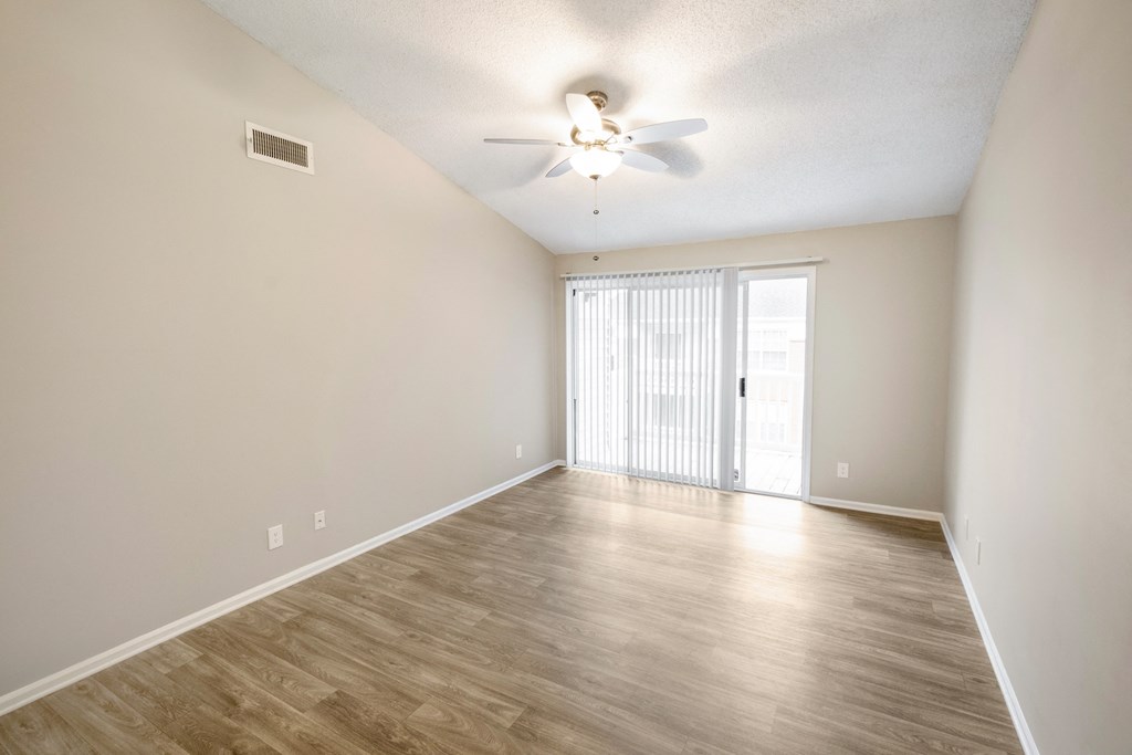 an empty living room with a ceiling fan and a window