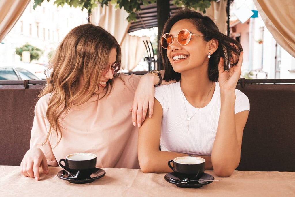 two women sitting at a table with cups of coffee