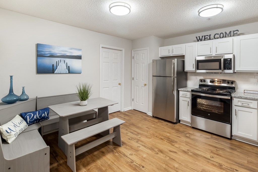 an open kitchen and living room with stainless steel appliances and white cabinets