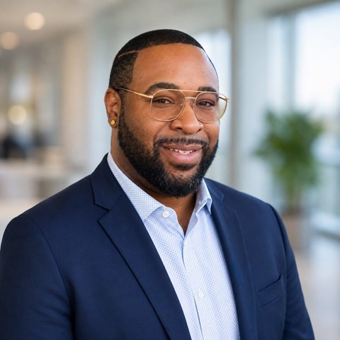 A man with glasses and a beard is wearing a blue suit.