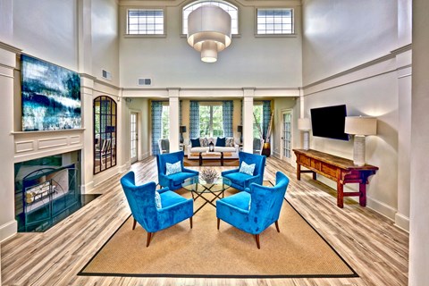 A living room with blue chairs and a fireplace.