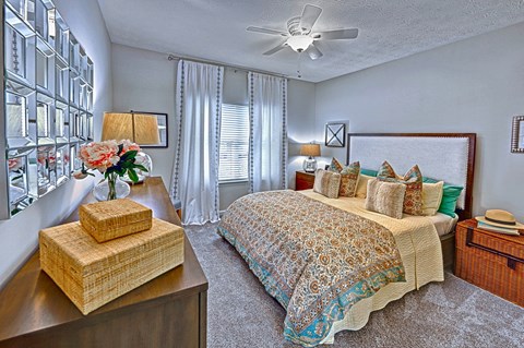 A bedroom with a bed, nightstand, and a vase of flowers.