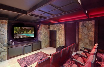 a media room with a large screen tv and a stone wall - Photo Gallery 25