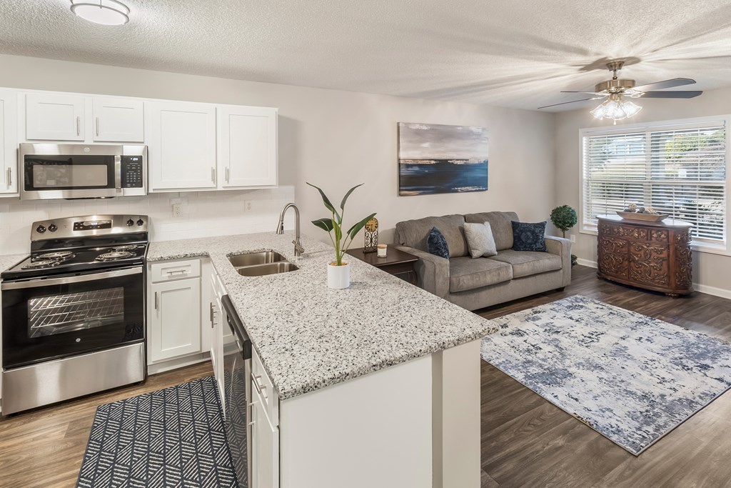 an open kitchen and living room with a granite counter top