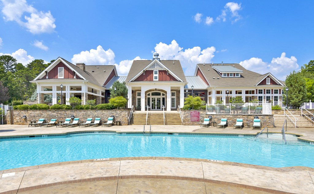 a large swimming pool with a house in the background