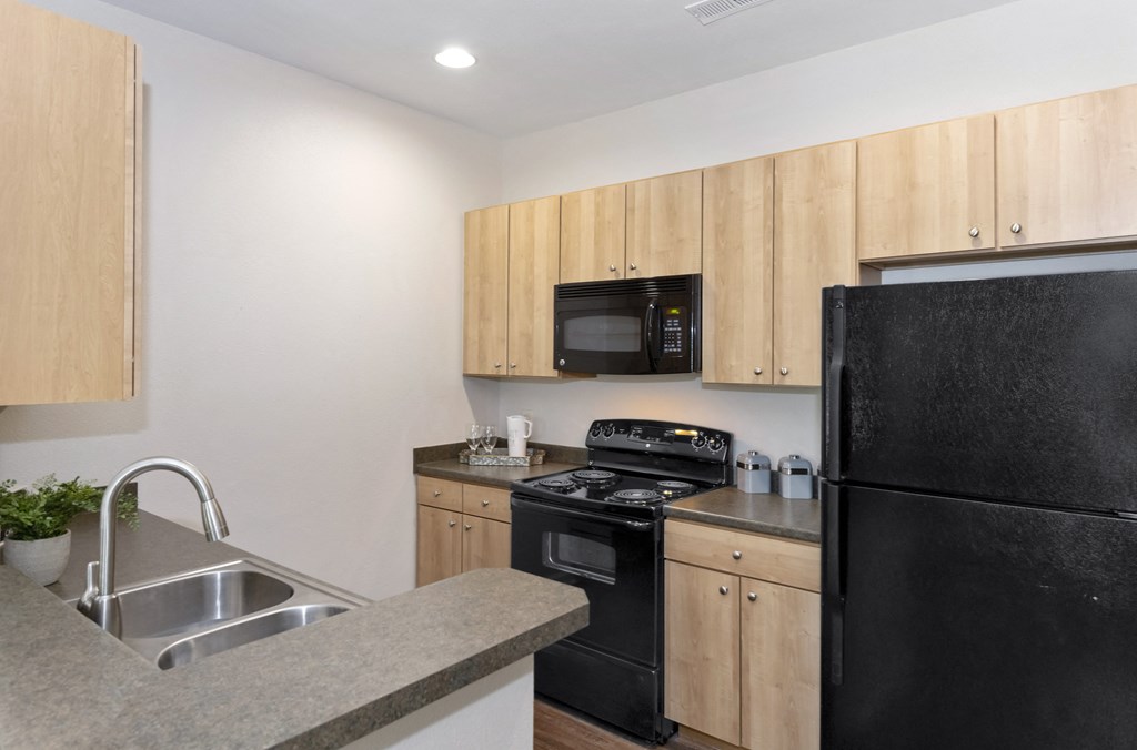 an empty kitchen with black appliances and wooden cabinets