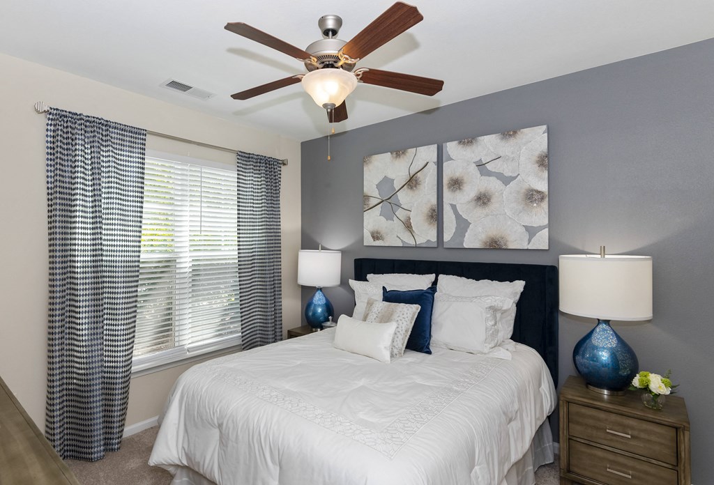 a bedroom with a large white bed and a ceiling fan