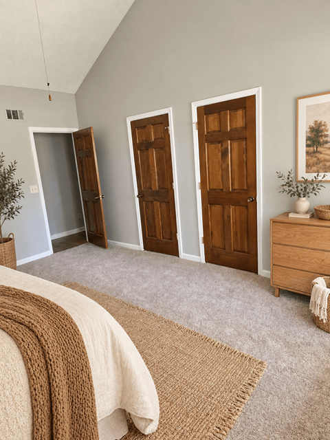 A room with a bed, a dresser, and three doors.