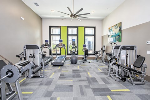 A gym with a variety of equipment including treadmills, weights, and exercise machines.