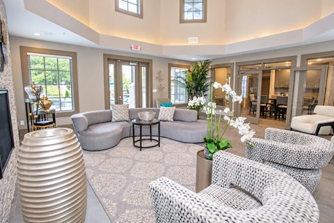 A living room with a large sofa and a round table with a vase of flowers on it.