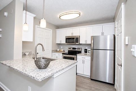 A kitchen with a granite countertop and stainless steel appliances.